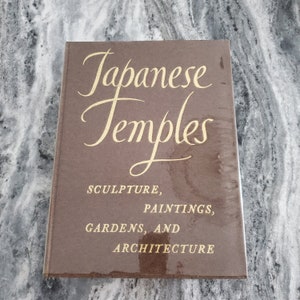 May include: A brown hardcover book with the title "Japanese Temples" in gold script. The subtitle reads "Sculpture, Paintings, Gardens, and Architecture".