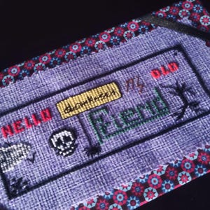 Puede incluir: Tela morada con un diseño de punto de cruz que presenta las palabras "Hello darkness my old friend" y una calavera. La tela está bordeada con un ribete estampado en negro y rojo.