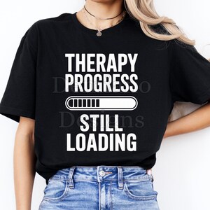 May include: Black t-shirt with the text "THERAPY PROGRESS" above a loading bar graphic, and "STILL LOADING" below. The shirt is worn with blue jeans. The bottom of the image includes the text "300DPI/ PNG /DIGITAL FILE".