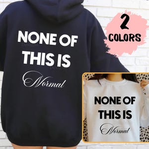 May include: Black hooded sweatshirt with the text "NONE OF THIS IS Normal" in white. A smaller image shows a white sweatshirt with the same text. The image also includes the text "2 COLORS".