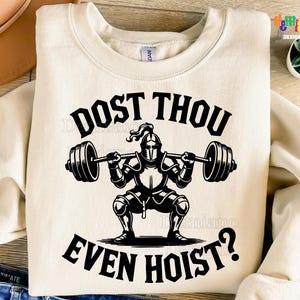 May include: Cream-colored sweatshirt with a black graphic of a knight lifting weights, and the text "DOST THOU EVEN HOIST?". The design includes a barbell and a squatting knight. The bottom of the image reads "300DPI/ SVG + PNG/DIGITAL FILE".