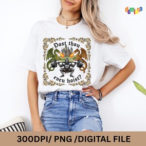 May include: White t-shirt featuring a medieval-themed graphic. The design includes a knight lifting weights, flanked by green and brown dragons, with a castle in the background. The text reads "Dost thou even hoist?"