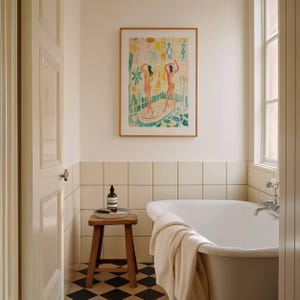 May include: A bathroom scene featuring a framed artwork with two figures, a wooden stool with a tray, and a white bathtub. The room has cream-colored walls and black and white checkered flooring. A towel is draped over the tub's edge, and a bottle of soap sits on the stool.