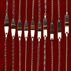May include: Nine gold-toned bracelets with various chain styles and clasp designs are displayed against a deep red background. Each bracelet features a different chain link pattern, including oval, figaro, and delicate bead chains. Some have rectangular nameplates. The product codes are visible.