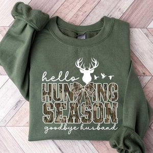 May include: Green sweatshirt with a white graphic that says "hello hunting season goodbye husband" with a camouflage pattern and a white deer silhouette.