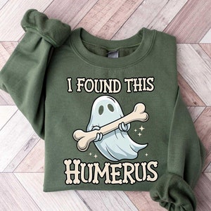 May include: A green sweatshirt with a white ghost holding a bone and the text "I found this humerus".