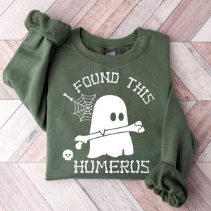 May include: Green sweatshirt with a white ghost holding a bone and the text "I found this humerus".