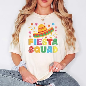 May include: A white t-shirt with a colorful graphic of a sombrero and the text "Fiesta Squad".