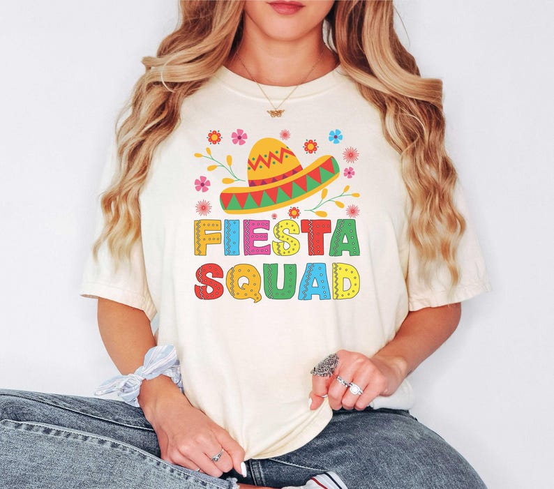 May include: A white t-shirt with a colorful graphic of a sombrero and the text "Fiesta Squad".