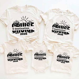 May include: A collection of cream-colored t-shirts and a onesie, each printed with a black graphic. The graphic includes the word "Cruise", palm trees, a sun, and the text "Destination 2026".