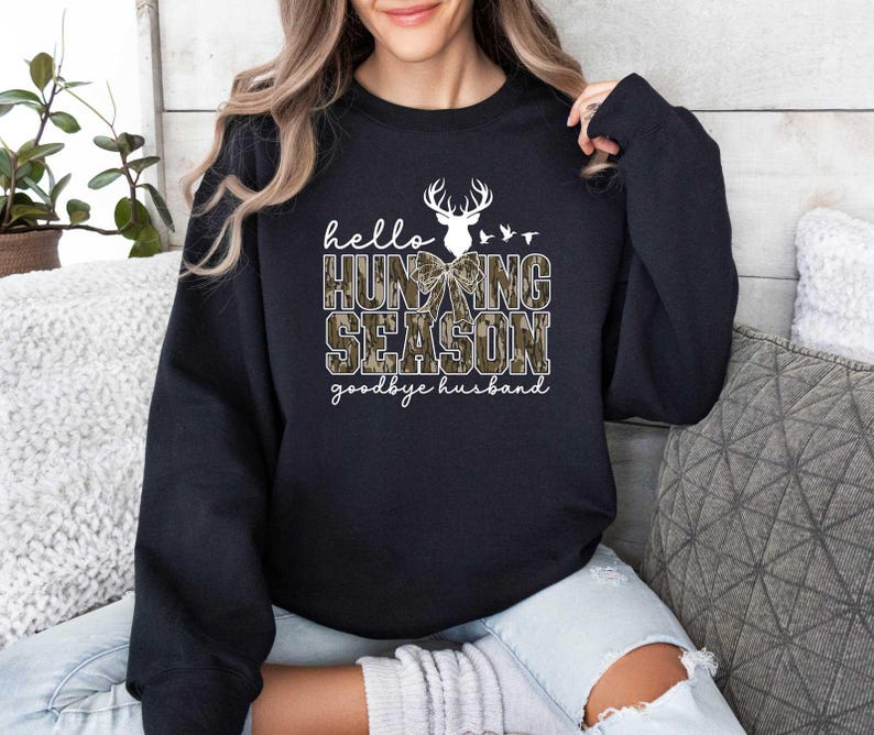May include: Black sweatshirt with a white deer head and the text "hello hunting season goodbye husband".