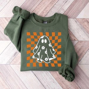 May include: A green sweatshirt featuring a white ghost with a flower pattern on a checkered orange and white background.