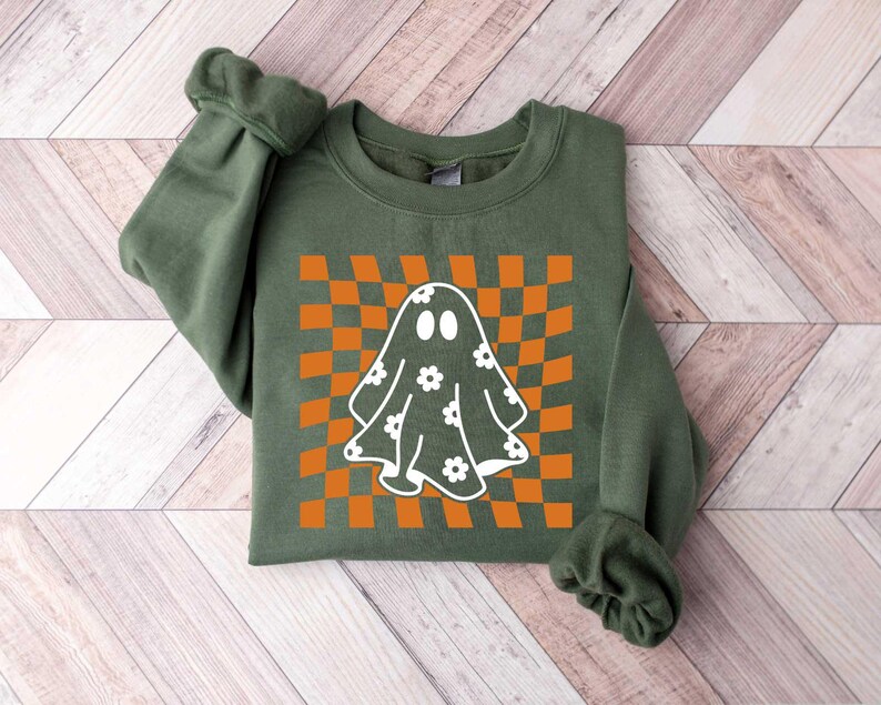 May include: A green sweatshirt featuring a white ghost with a flower pattern on a checkered orange and white background.