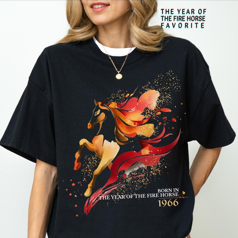 Pu&ograve; includere: T-shirt nero con un design stilizzato di cavallo nei toni dell'arancione, rosso e oro, con il testo "THE YEAR OF THE FIRE HORSE FAVORITE" e "BORN IN THE YEAR OF THE FIRE HORSE 1966".