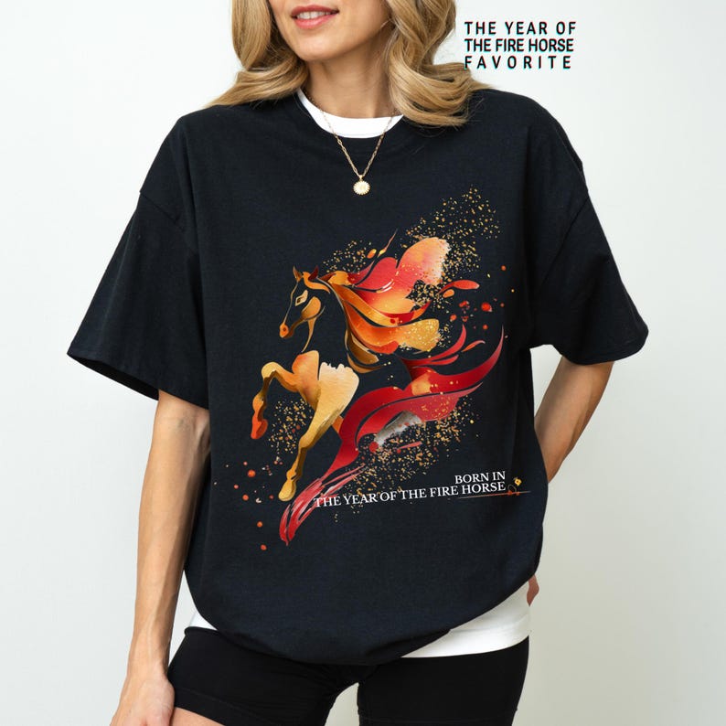 Pu&ograve; includere: T-shirt nero con un'illustrazione ad acquerello di un cavallo nei toni del rosso e dell'arancione. La maglietta presenta il testo "THE YEAR OF THE FIRE HORSE FAVORITE" e "BORN IN THE YEAR OF THE FIRE HORSE".