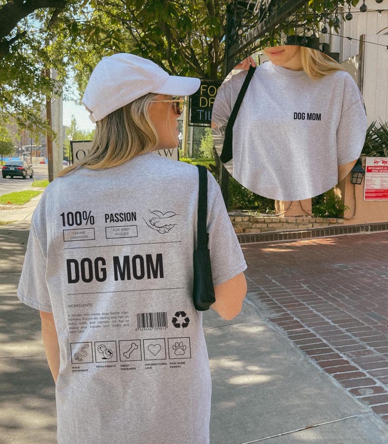 May include: Gray t-shirt with the text "DOG MOM" on the front and a graphic on the back that says "100% Passion Dog Mom" with a list of ingredients: "A person who treats their dog better than themselves.  You can find them walking their dog, playing fetch, and caring for their dog's needs.  They handle vet visits and other stressful situations with grace and patience."