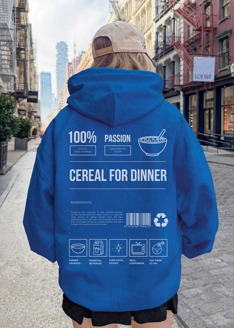 Może przedstawiać: Niebieska bluza z kapturem z białym napisem "100% PASSION" i "CEREAL FOR DINNER". Z tyłu znajduje się grafika miski z płatkami śniadaniowymi i inne ikony. Bluza jest noszona przez osobę w środowisku miejskim.