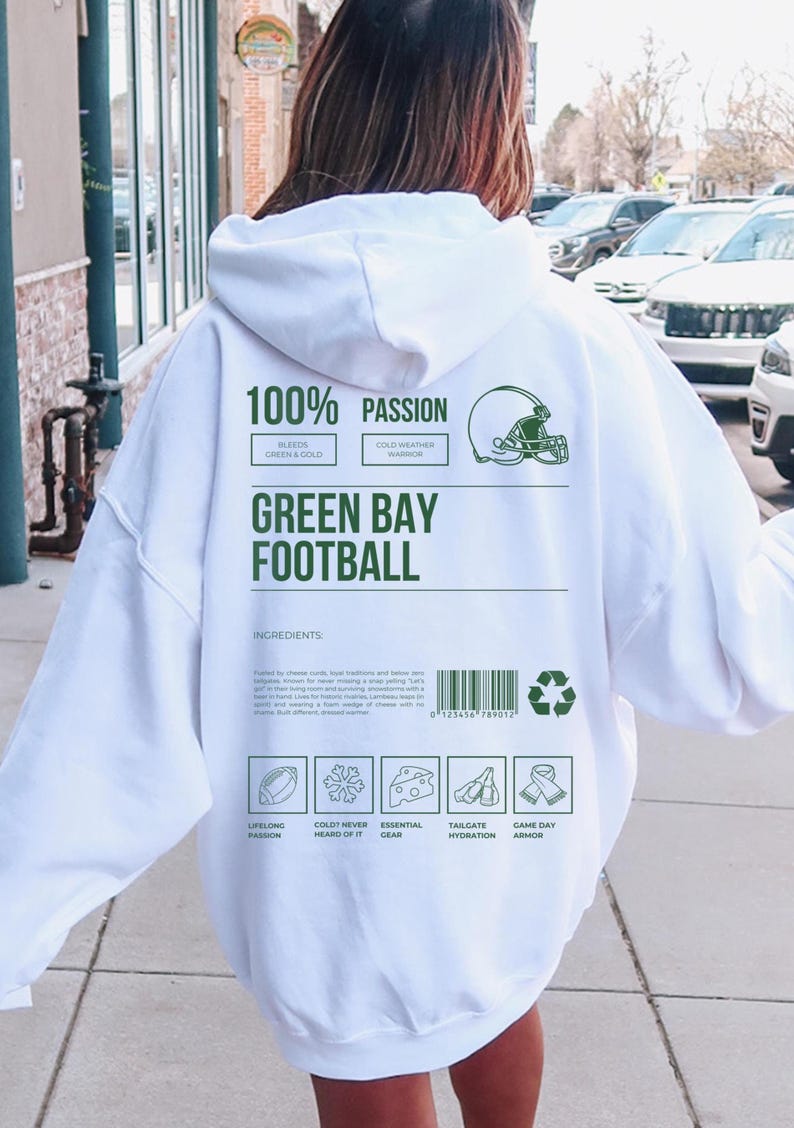 May include: White hoodie with green text reading "100% PASSION" and "GREEN BAY FOOTBALL". The back of the hoodie features a football helmet graphic and ingredient icons. A casual, comfortable garment.