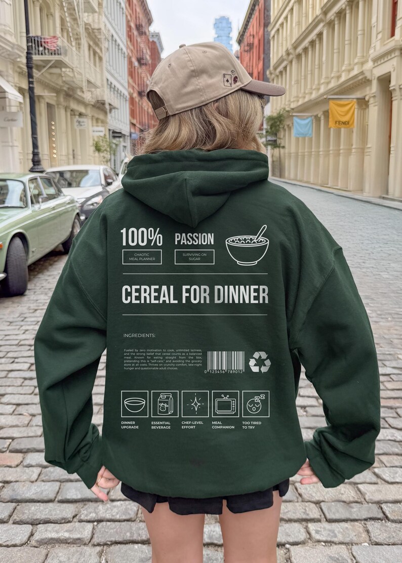 Może przedstawiać: Ciemnozielona bluza z kapturem z napisem "CEREAL FOR DINNER" oraz innymi tekstami i grafikami. Bluza z kapturem ma kaptur i długie rękawy. Tekst zawiera "100% PASSION" i "INGREDIENTS".