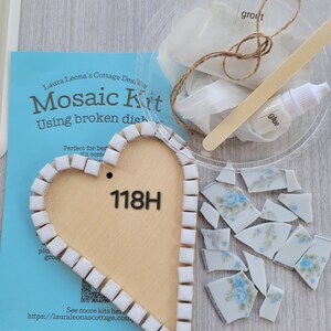 May include: A mosaic kit with a wooden heart-shaped base, white square tiles, and broken pieces of a floral patterned dish. Includes grout, glue, and a wooden mixing stick. The kit is labeled "Mosaic Kit" and "118H".