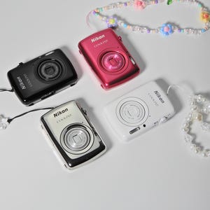 Nikon Coolpix S01: la cámara digital más pequeña y exclusiva jamás fabricada. Incluye: funda, lector de tarjetas SD, batería y cargador.