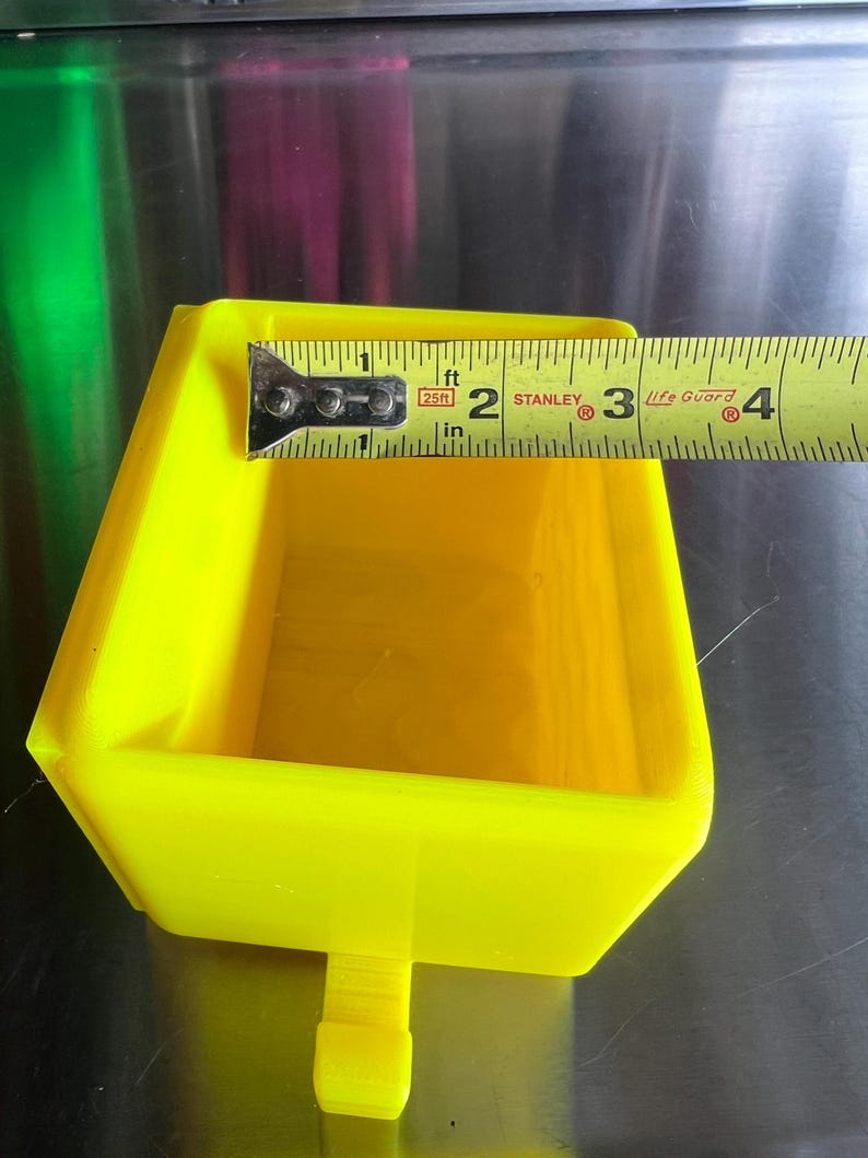 May include: A bright yellow plastic tray with a small handle on the bottom. The tray is 2 inches wide and 3 inches long. The tray is made of a durable plastic and is perfect for holding small items.
