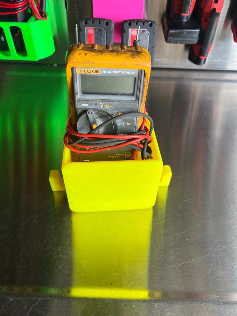 May include: A yellow plastic holder with a black and yellow Fluke 78 Automotive Meter inside. The meter has a digital display and a red knob.