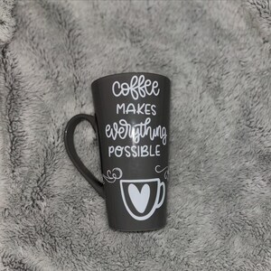 May include: Gray ceramic coffee mug with a white design that says "coffee makes everything possible" and a small heart-shaped coffee cup graphic.