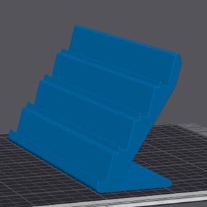 May include: A blue, angled display stand with four stepped levels. The stand is designed to hold and showcase items. The stand is made of a solid material and has a clean, modern design.