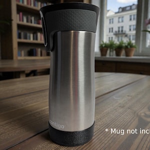 May include: A stainless steel Contigo travel mug featuring a brushed silver finish, a black lid with a textured grip section, and a black base. The brand name Contigo is printed in white near the bottom of the cylindrical body of the beverage container.