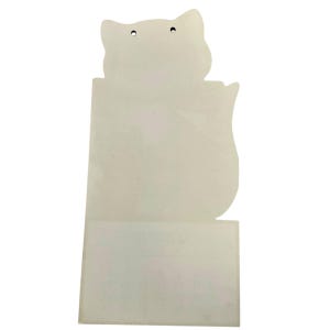 Puede incluir: Un recorte de papel en forma de gato de color crema con dos peque&ntilde;os agujeros en la parte superior para colgar. El recorte tiene una base rectangular y un dise&ntilde;o de silueta de gato. El papel tiene una superficie ligeramente texturizada.
