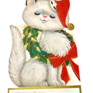 Puede incluir: Una tarjeta navide&ntilde;a vintage con un gato blanco que lleva un gorro de Pap&aacute; Noel y una corona de acebo. El gato tiene los ojos azules cerrados y una nariz rosa. Un gran lazo rojo adorna el pecho del gato, y una campana dorada cuelga del sombrero.