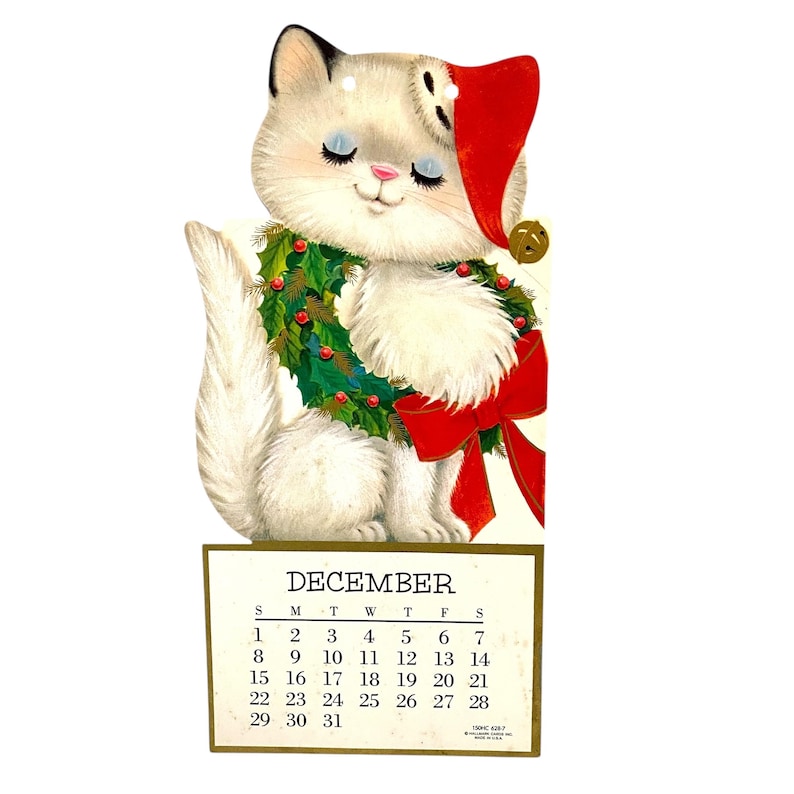 Puede incluir: Calendario navide&ntilde;o vintage con un gato blanco con gorro de Pap&aacute; Noel y una corona. El gato tiene los ojos cerrados y un lazo rojo. El calendario muestra el mes de diciembre.