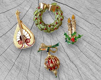 May include: A collection of vintage Christmas brooches. Includes a gold-toned lute, a wreath with a gold bow, a pair of candles with holly, and a red and gold ornament with a bow. The brooches are set against a gray wood grain background.