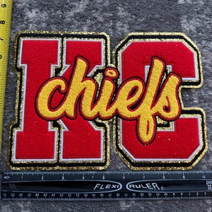 May include: Red, white, and gold felt patch with the letters "KC" and the word "chiefs" in a yellow script font.