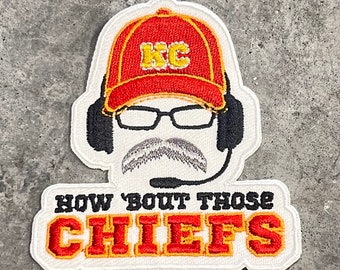 May include: White embroidered patch with a cartoon of a person wearing a red baseball cap with the letters "KC" in yellow, glasses, a mustache, and a headset. The text "HOW 'BOUT THOSE CHIEFS" is below the cartoon in red and yellow letters.