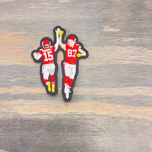 May include: Two red and white football players high-five each other. The player on the left is wearing number 15 and the player on the right is wearing number 82.