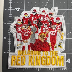 May include: Embroidered patch featuring a football team in red and white uniforms, holding a trophy. The patch includes the text "WELCOME TO THE RED KINGDOM" in yellow and white.