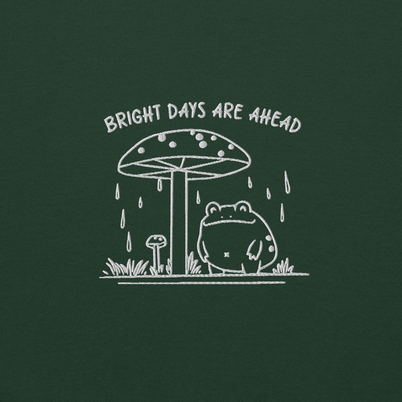 Threadmire © - Get ready to hop into cozy vibes with our Embroidered Cute Frog Under Mushroom Shirt, a whimsical nature tee that’s perfect for animal lovers and those who appreciate positive quotes! This delightful sweatshirt not only keeps you comfy