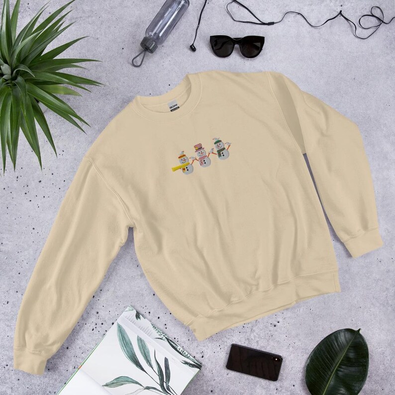 Celebrate the magic of the holidays with this Festive Snowmen Embroidered Sweatshirt, featuring a delightful trio of snowmen and adorable birds. ❄️☃️ Perfect for cozying up by the fire, holiday parties