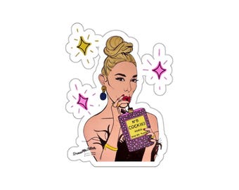 May include: A sticker featuring a pop art style illustration of a woman holding a perfume bottle. The bottle is purple with the text "N°5 Cockies Paris Eau de Plaisir". The woman has blonde hair, red lipstick, and is wearing gold jewelry. Pink and yellow starbursts surround her.