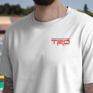 May include: White t-shirt with a red "TRD" logo and the text "Toyota Racing Development" above it.