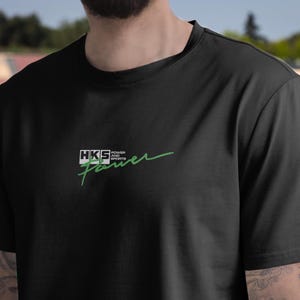 May include: Black t-shirt with a green HKS Power and Sports logo.
