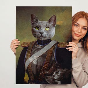 May include: A portrait of a gray cat with yellow eyes, dressed in a military uniform with gold accents. The cat's face is the focal point, set against a blurred green and brown background. The artwork is held by a person.