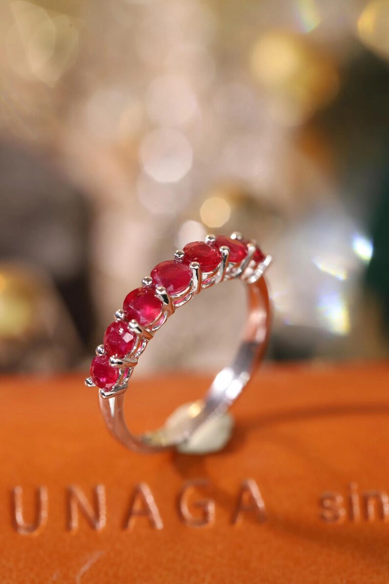 Pu&ograve; includere: Un anello color argento con una fila di sei rubini rotondi di un rosso vibrante, montati su griffe individuali. La fascia &egrave; lucida e metallica, caratterizzata da un design pulito che mette in risalto il colore cremisi delle pietre.