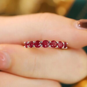 Pu&ograve; includere: Un anello in argento con sette rubini taglio rotondo di colore rosso intenso disposti in fila. Le pietre sono fissate da piccole griffe in argento, creando una linea continua di vivaci gemme rosse lungo la fascia metallica.