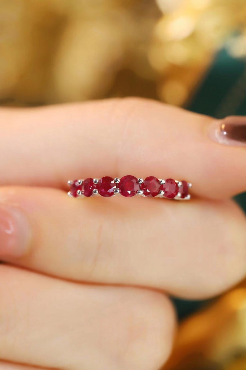Pu&ograve; includere: Un anello in argento con sette rubini taglio rotondo di colore rosso intenso disposti in fila. Le pietre sono fissate da piccole griffe in argento, creando una linea continua di vivaci gemme rosse lungo la fascia metallica.