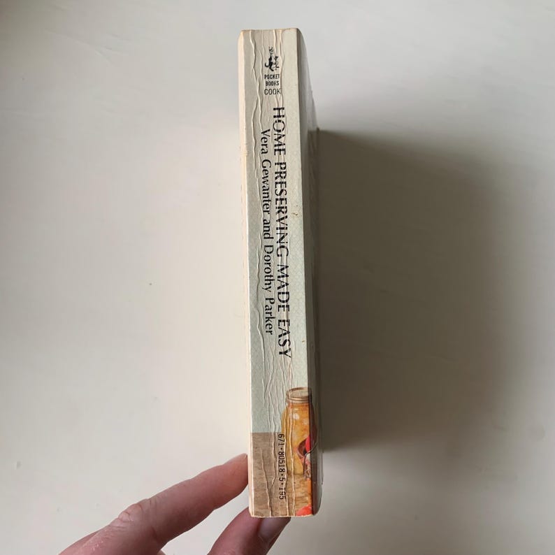 May include: A vintage paperback book titled "Home Preserving-Made Easy" by Vera Gewanter and Dorothy Parker. The book cover features a jar of preserved fruit with a red lid and a green stem.