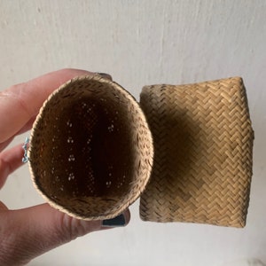 May include: Two woven baskets made from natural straw. One basket is open and the other is closed. The open basket has a woven pattern with holes.