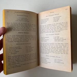 May include: A vintage cookbook page with recipes for raspberry vinegar, simple pickles, bread and butter pickles, dill cucumber pickles, sour cucumber pickles, and sweet cucumber pickles. The recipes include ingredients and instructions for making each type of pickle.